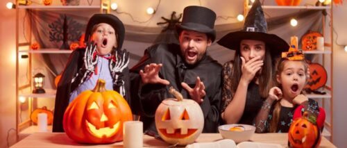 A family trying to look scary on halloween while surrounded by pumpkins, candy, and decorations