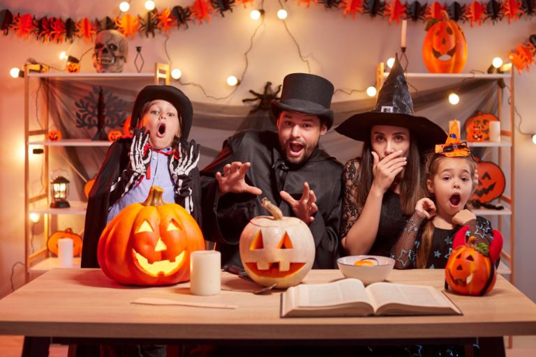 A family trying to look scary on halloween while surrounded by pumpkins, candy, and decorations
