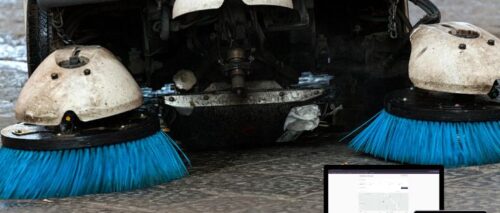 Street sweeper vehicle cleaning a city roadway with digital route tracking and performance analytics overlay.
