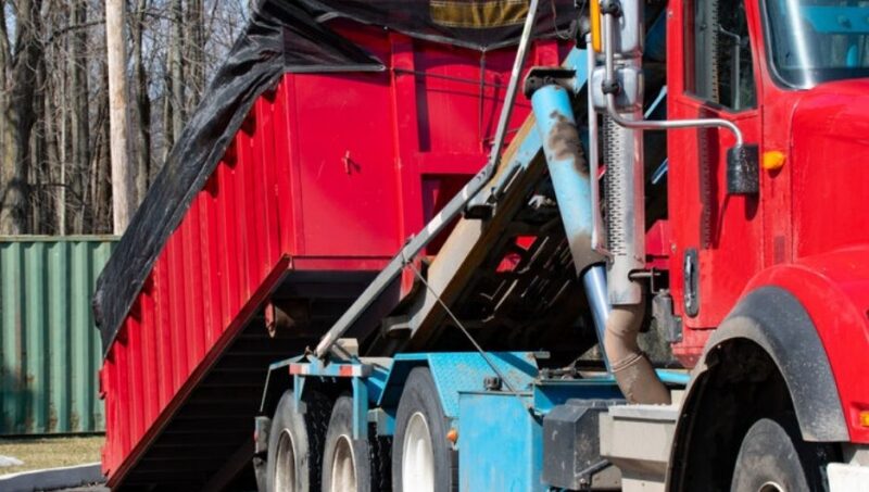 Waste collection truck in North America picking up dumpster